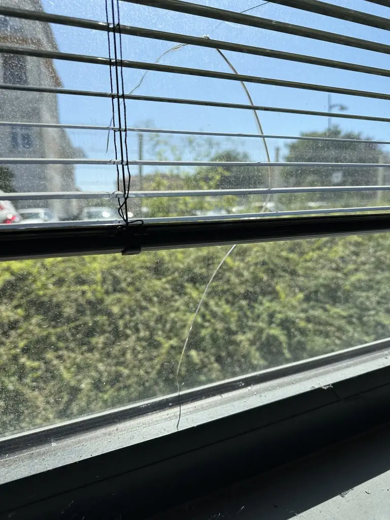 Vitre fissurée par choc thermique: exemple de casse thermique sur fenêtre exposée au soleil, fissures rayonnantes visibles.